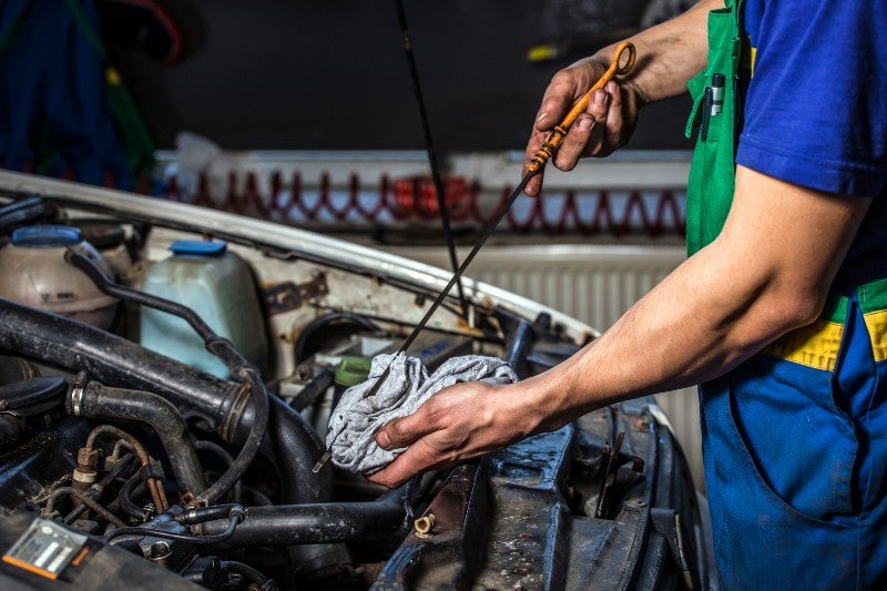 Car technician checking oil in a service shop